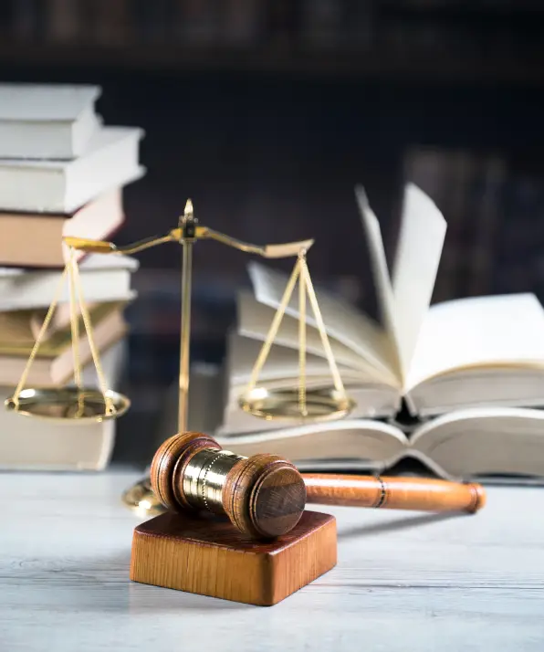 A wooden gavel rests on a square block, with a golden balance scale and partially opened books in the background, symbolizing justice A wooden gavel rests on a square block, with a golden balance scale and partially opened books in the background, symbolizing justice