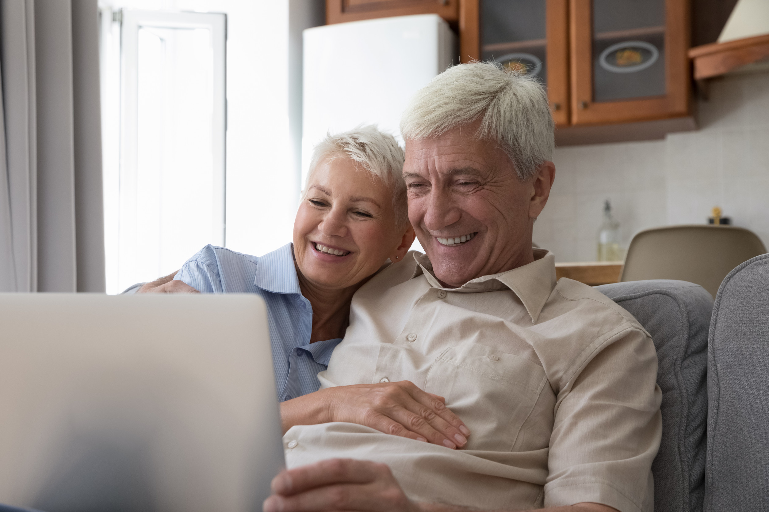 Happy middle aged 60s couple sitting on couch at home